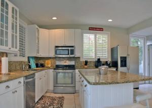 a kitchen with white cabinets and stainless steel appliances at Edgemere in Siesta Key +30 photos