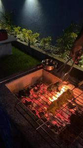 una persona che cucina cibo su una griglia di notte di ECR Beach Villa with Private Swimming Pool a Tirupporūr
