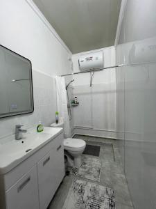a white bathroom with a toilet and a sink at Tabylga guest house in Jalal-Abad +47 photos