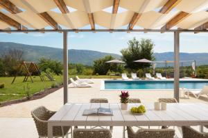 a patio with a table and chairs and a pool at Villa Roti by Rent Istria in Kostrčani
