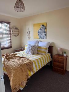a bedroom with a bed with a yellow and white comforter at Pet friendly beach cottage in Victoria in Paradise Beach +33 photos