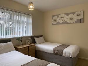 1 dormitorio con 2 camas y una ventana con flores en la pared en Durham Stay 2BR, en Durham 12 fotos más