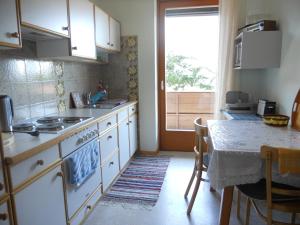 eine Küche mit einem Herd, einem Tisch und einem Fenster in der Unterkunft Ferienwohnung Gerti Kalt in Lieserhofen