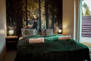 een slaapkamer met een bed met een hert aan de muur bij Domki Natura Zator in Graboszyce