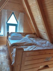 a bed in a log cabin with a window at Pax Montana in Blidinje