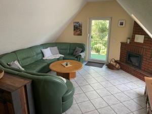 een woonkamer met een groene bank en een open haard bij Ferienhaus in Elend in Elend