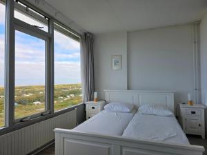 a bedroom with a white bed and a large window at Appartementencomplex Juliana 162 in De Koog