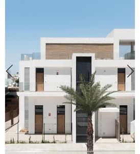 un bâtiment blanc avec un palmier devant dans l'établissement Casa Bakara la Brisa Zahara beach, à Zahara de los Atunes