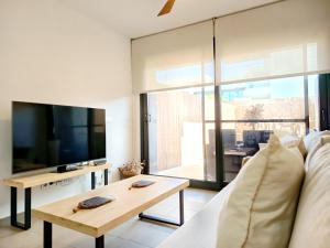 un salon avec un canapé, une télévision et une table dans l'établissement Casa Bakara la Brisa Zahara beach, à Zahara de los Atunes