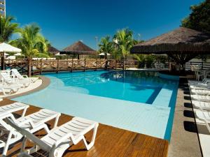 una gran piscina con sillas y sombrillas blancas en Apartamento Suites Le Jardin Caldas Novas Goiás, en Caldas Novas