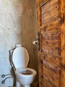 a bathroom with a toilet and a wooden door at Gazrashek Siwa Hot spring& trips Haven in Siwa +80 photos