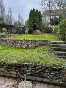 a stone wall in a yard with trees and a house at Ferienhaus "Hagen" in Schkopau in Schkopau
