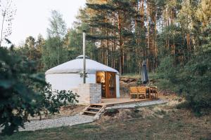 a yurt with a table and chairs in a forest at Gajurta in Rudnica