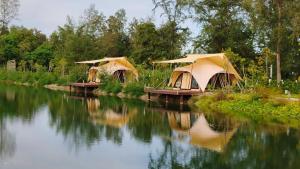a couple of tents sitting on the side of a river at Camp Cayla - COASTA in Ban Ao Makham Pom