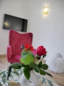 un vaso con rose davanti a una sedia rosa di Le Paon du jour en Touraine a Veigné