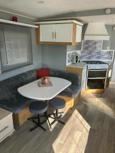a small kitchen with a white table and a couch at 8 Berth 3 bed caravan pet friendly TP56 in Chapel Saint Leonards