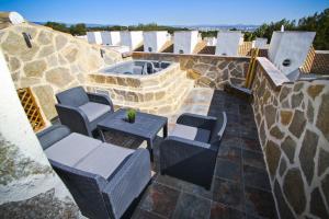a patio with chairs and a hot tub on a stone wall at NATURE PLUS Family House in Salou