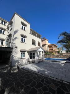 a large white building with a fence in front of it at Rooftop d'exception - calme et confort à Grand Baie in Grand Baie