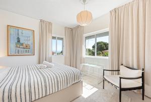 ein Schlafzimmer mit einem Bett und einem Stuhl und Fenstern in der Unterkunft Villa Victoria, Torremolinos in Torremolinos