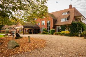 een groot bakstenen huis met een oprit ervoor bij Landgoed De Wilmersberg in De Lutte