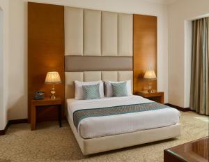 a bedroom with a large bed with two tables and two lamps at Gewan Hotel Cairo in Cairo
