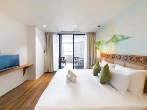 a large white bed in a room with a tv at Gold Central Hotel by Haviland in Da Nang
