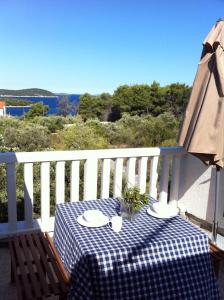 a table with a checkered table cloth on a balcony at Apartments Voga in Maslinica