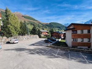 ein Parkplatz mit vor einem Gebäude geparkten Autos in der Unterkunft Les 2 Alpes - Charmant apt rénové 2 chambres, balcon, proche pistes - FR-1-546-32 in Les Deux Alpes