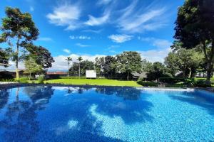 une grande piscine avec un ciel bleu et des arbres dans l'établissement Tjapoeng Resort Pancawati, à Ciherangsating