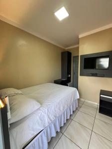 a bedroom with a bed and a flat screen tv at Du Vale Hotel in Tomé-Açu