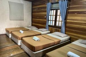 quatre lits dans une pièce aux murs et fenêtres en bois dans l'établissement Tjapoeng Resort Pancawati, à Ciherangsating 54 autres photos