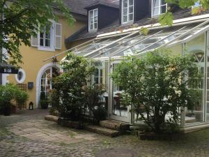 ein Haus mit einem Gewächshaus und Bäumen davor in der Unterkunft Hotel Altes Pfarrhaus Beaumarais in Saarlouis