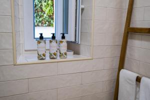 ein Badezimmer mit drei Flaschen auf einem Regal in einem Spiegel in der Unterkunft Zus House Private Pool Retreat Near Lisbon & Beach in Parede + 34 Fotos
