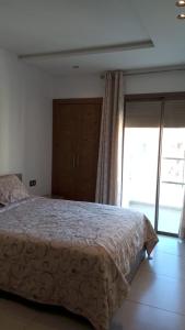 a bedroom with a bed and a large window at Superbe appartement A33 in Kenitra +6 photos