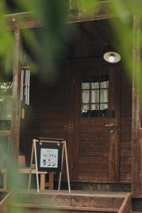 a front door of a wooden house with a sign in front at ウバク荘 Ubakuso in Biei