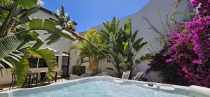 a swimming pool in a garden with purple flowers at Villa Cleo, vistas de ensueño in San Miguel de Abona