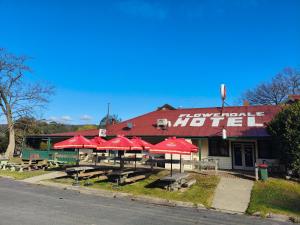 FlowerdaleにあるFlowerdale Hotelの目の前にテーブルと赤い傘が置かれたレストラン