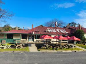 FlowerdaleにあるFlowerdale Hotelの目の前にテーブルと赤い傘が置かれたレストラン