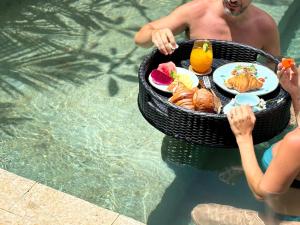 a man holding a basket of food in a swimming pool at MINTU Villa Uluwatu - BBQ, Private Pool & Concierge Service in Bingin Beach