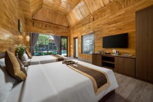 a bedroom with two beds and a flat screen tv at Tam Coc Orchid Hotel & Spa in Ninh Binh