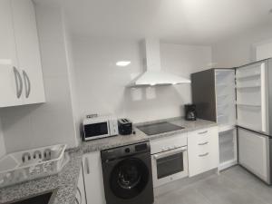 eine weiße Küche mit Waschmaschine in der Unterkunft Velez Malaga 2 Dorm 4 Huésped Piscina Parking WiFi in Vélez-Málaga
