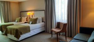 a hotel room with two beds and a chair at abba Presidente Suites Santiago in Santiago