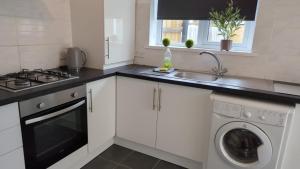 Una cocina blanca con fregadero y lavavajillas. en Hebburn 3 bed House, en South Shields 13 fotos más