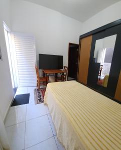 a bedroom with a bed and a table and a desk at Quarto c banheiro para uma pessoa in Poços de Caldas +4 photos