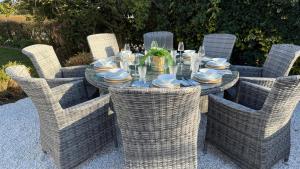 einen Esstisch mit Korbstühlen und eine Tableasteryasteryasteryasteryastery in der Unterkunft Bramble Cottage in Criccieth