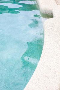 a swimming pool with blue water next to a curb at Tallows Townhouse in Byron Bay