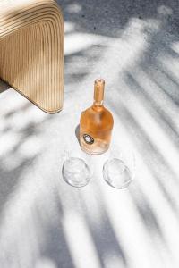 a bottle and two wine glasses sitting on the ground at Tallows Townhouse in Byron Bay