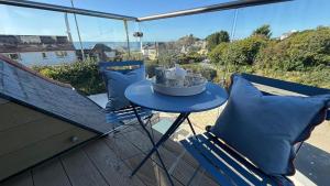 einen Tisch auf einem Balkon mit 2 Stühlen und einem Tisch mit Tassen in der Unterkunft Bramble Cottage in Criccieth