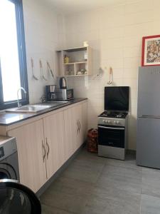 a kitchen with a stove and a sink and a refrigerator at Appartement aux Mamelles in Dakar