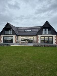 a house with a black roof and a green yard at Rumblekirn in Annan